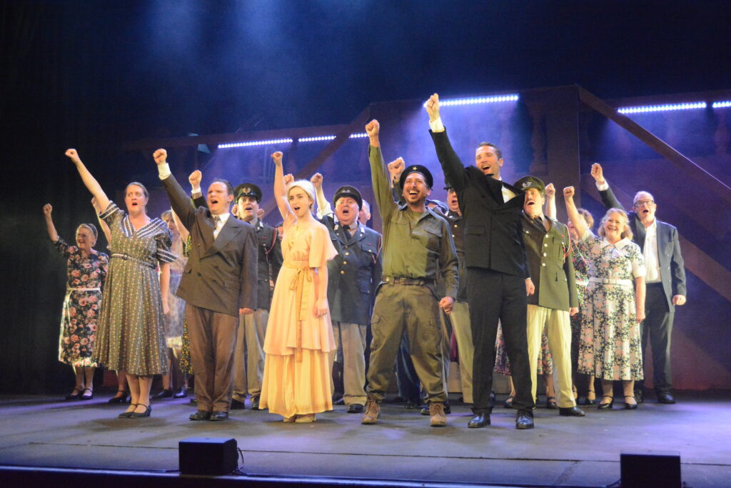 Evita finale - group of people in 1940s costumes with fists raised
